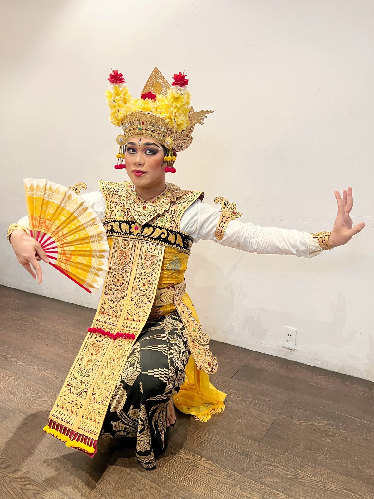 金糸の衣装をまとい扇を手に舞うバリ舞踊の踊り手